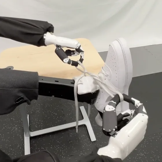 A humanoid robot tying the laces of a sneaker
